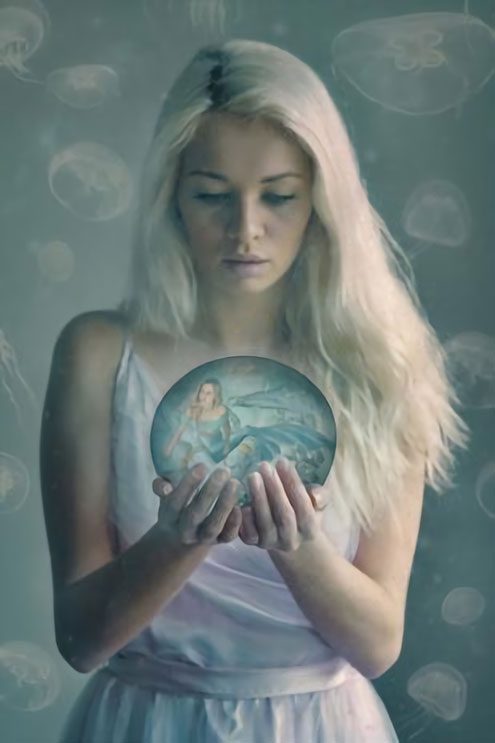 A woman holding a crystal ball with a picture of a mermaid.