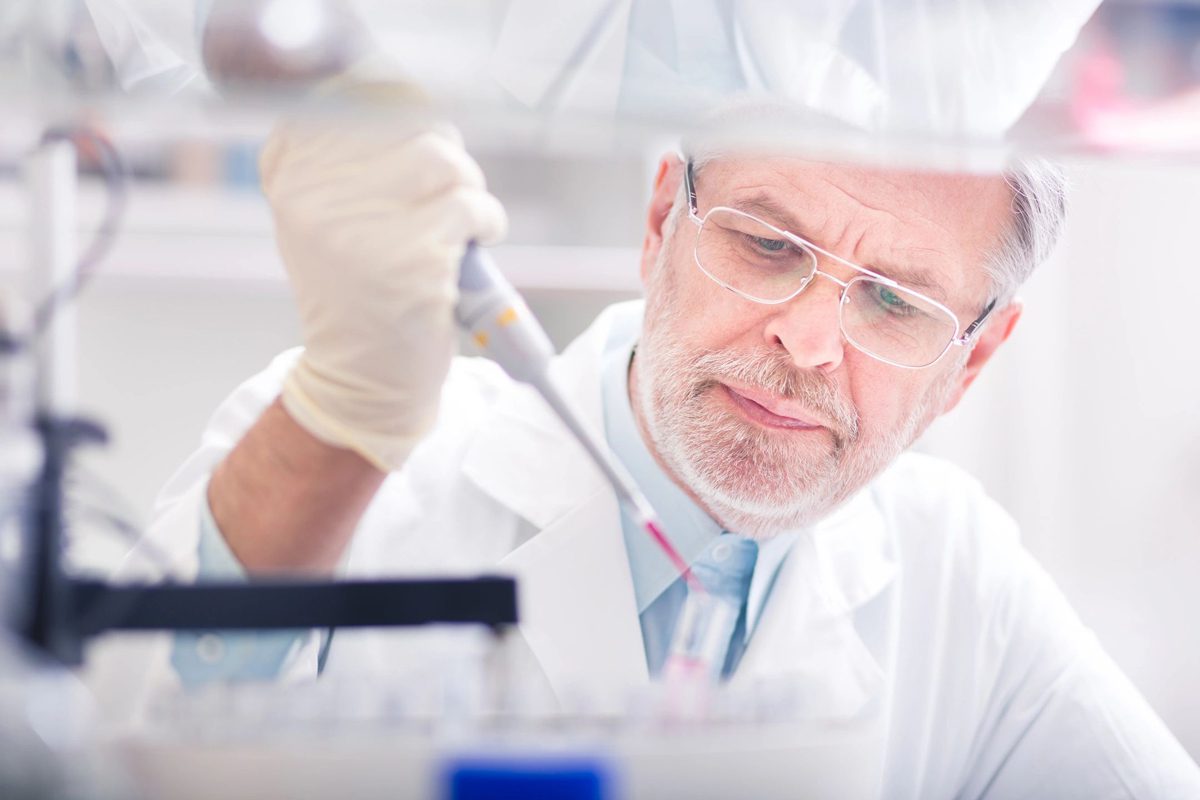 A man in white lab coat and glasses working.
